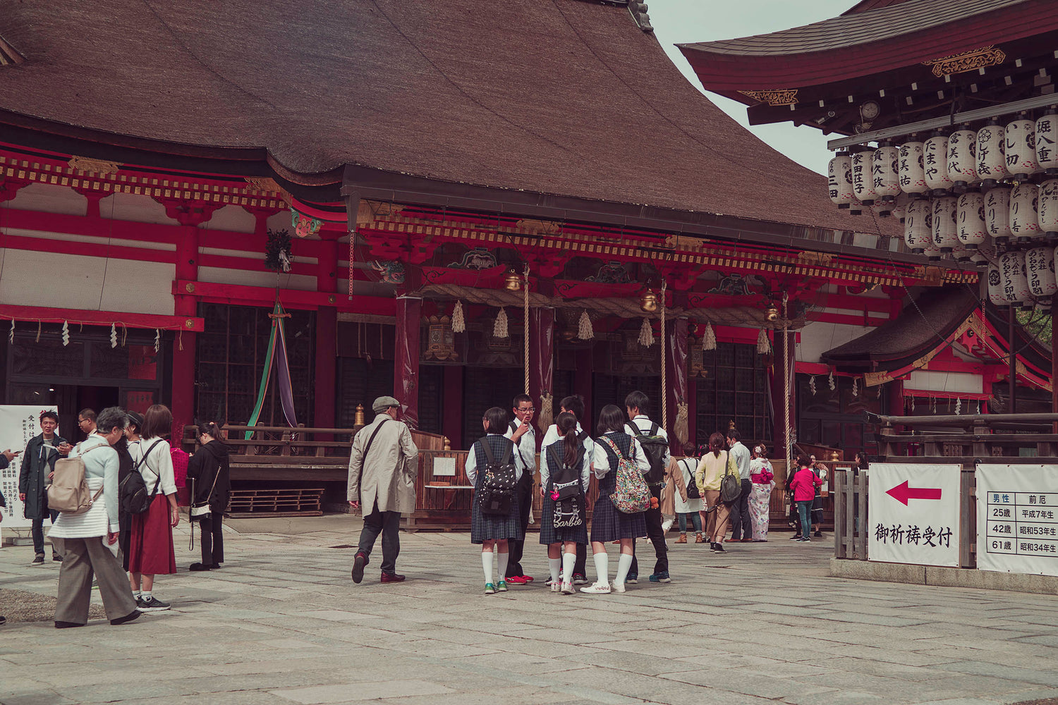 A gathering of locals and students on a field trip to a temple shrine in the Gion area of Kyoto Japan while celebrating at the Cherry Blossom Festival. 